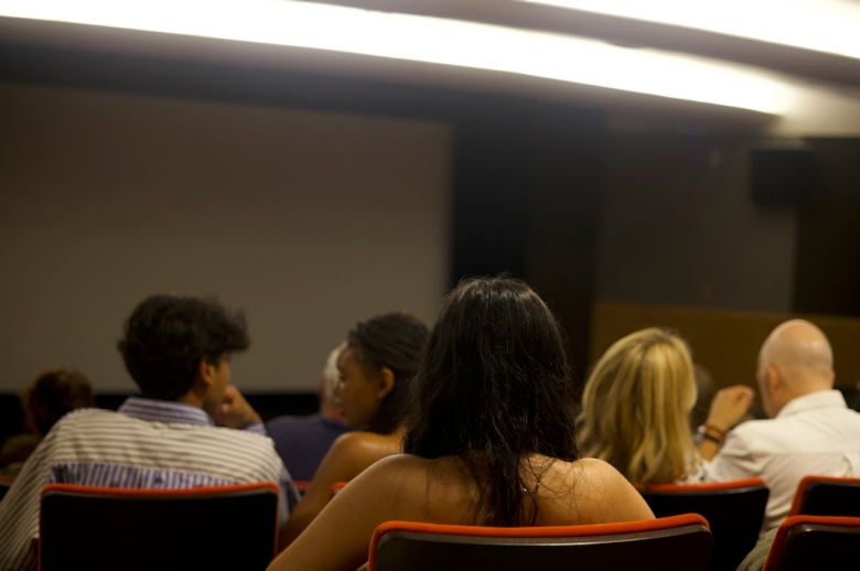 Photo taken behind a group of the High School Filmmakers Workshop students sitting in a theatre-style classroom.